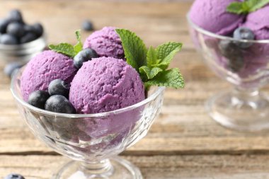 Yaban mersinli şerbet ve tatlı kaselerinde nane, ahşap masada, yakın plan.