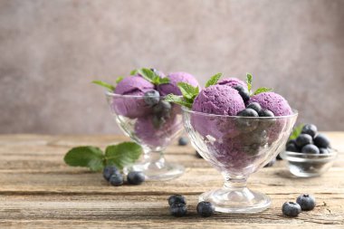 Yaban mersinli şerbet ve tatlı kaselerinde nane, ahşap masada, gri arka planda, yakın planda.