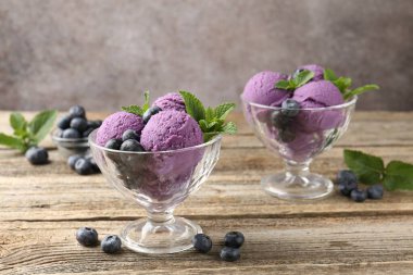 Yaban mersinli şerbet ve tatlı kaselerinde nane, ahşap masada, gri arka planda, yakın planda.