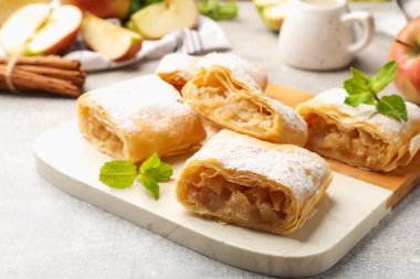 Lezzetli elmalı turta parçaları pudra şekeri ve açık gri masada nane şekeri, yakın plan.