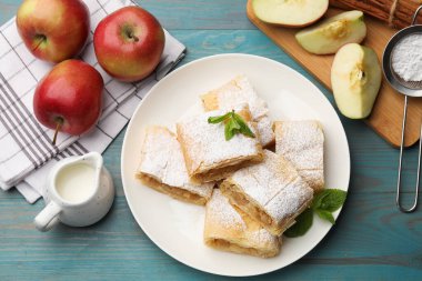 Lezzetli elmalı turta parçaları pudra şekeri, nane ve açık mavi ahşap masa üzerinde meyveler, düz yatıyordu.