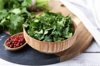 Taze yeşil kişniş ve beyaz ahşap masada biber, yakın plan.