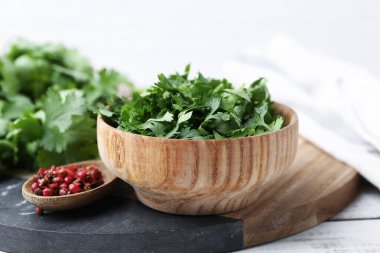 Taze yeşil kişniş ve beyaz ahşap masada biber, yakın plan.