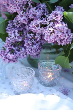 Güzel leylak çiçekleri, tabaklar ve yanan mumlar bahçede, yakın plan