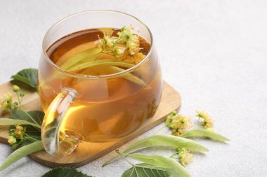 Fincanda taze ıhlamur çayı ve açık gri masada çiçekler, yakın plan. Metin için boşluk