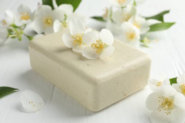 Sabun barı ve yasemin çiçekleri beyaz ahşap masada, yakın plan.