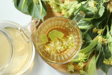 Lezzetli ıhlamur çayı, yapraklar ve çiçekler ışık masasında.