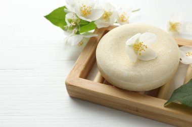 Sabun barı ve yasemin çiçekleri beyaz ahşap masada, yakın plan. Metin için boşluk