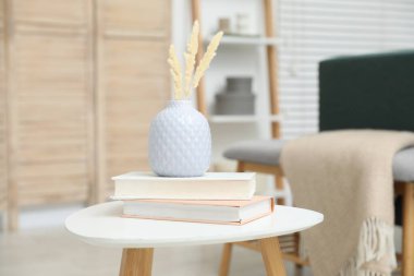 Vazoda kurumuş çiviler ve kapalı alanda beyaz masa üzerinde kitaplar.