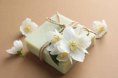 Açık kahverengi arka planda sabun ve yasemin çiçekleri, yakın plan.