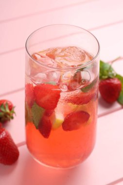 Çilekli içecek ve pembe ahşap masadaki buz, yakın plan.