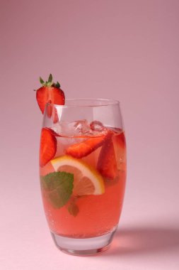 Pembe arka planda çilek, nane, limon ve buzlu içecek, yakın plan.