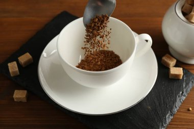 Tahta masaya granüle edilmiş hazır kahveyi koymak, yakın plan.