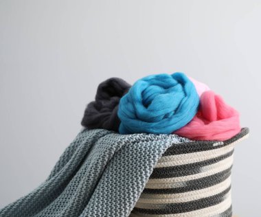 Yumuşak yün ve örgü ipliği sepetin içinde açık gri arka planda, yakın plan