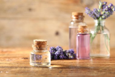 Ahşap masada lavanta şişeleri ve çiçekler, yakın plan.