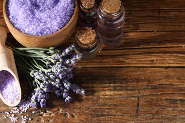 Lavanta şişeleri, ahşap masa üzerinde gerekli yağ ve çiçekler. Metin için boşluk