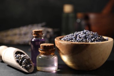 Siyah masanın üzerinde gerekli yağ ve lavanta çiçekleri, yakın plan.