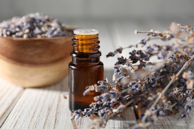 Beyaz ahşap masada doğal yağ ve lavanta çiçekleri, yakın plan.