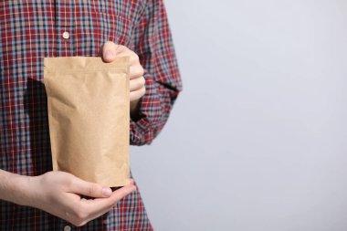 Açık gri arka planda fermuarlı stand-up çantası tutan kadın, yakın plan. Metin için boşluk