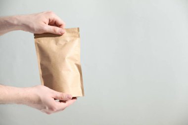 Açık gri arka planda fermuarlı stand-up çantası tutan kadın, yakın plan. Metin için boşluk