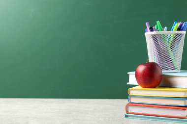 Farklı okul kırtasiyesi ve gri masada kırmızı elma karatahtaya karşı, metin için yer