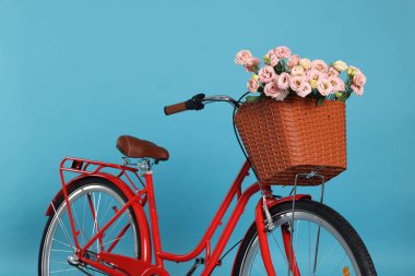 Açık mavi arka planda güzel çiçeklerle dolu bir bisiklet sepeti