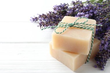 Sabun barları ve lavanta çiçekleri beyaz ahşap masada, yakın plan. Metin için boşluk