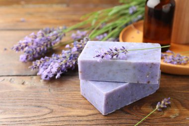 Sabun barları, diğer kozmetik ürünleri ve lavanta çiçekleri ahşap masada, yakın plan.