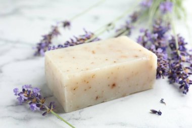 Sabun çubuğu ve lavanta çiçekleri beyaz mermer masada, yakın plan.