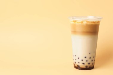 Bej arka planda plastik fincanda lezzetli sütlü çay, metin için yer