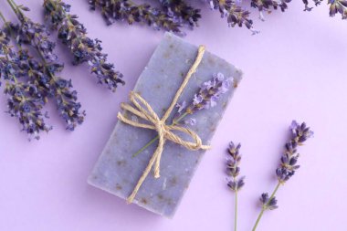 Aromatik sabun çubuğu ve mor arka planda lavanta çiçekleri.