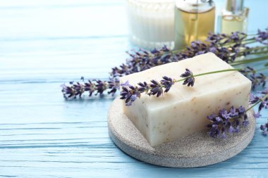 Aromatik sabun barı ve lavanta çiçekleri açık mavi ahşap masada, yakın plan. Metin için boşluk
