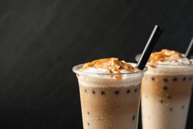 Siyah arka planda plastik fincanlarda lezzetli sütlü çay, yakın plan. Metin için boşluk