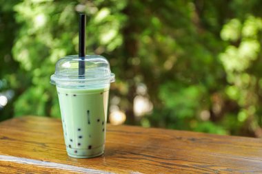 Tahta masada plastik bardakta lezzetli sütlü çay. Metin için boşluk