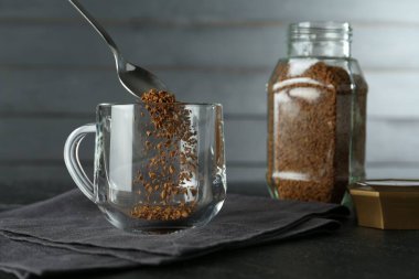 Siyah masada hazır kahveyi fincana koymak, yakın plan.