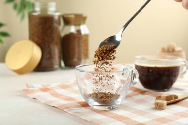 Işık masasında hazır kahveyi fincana koyan kadın, yakın plan.