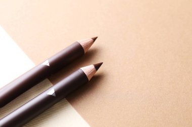 Bej arka planda farklı kaş kalemleri, yakın plan. Metin için boşluk