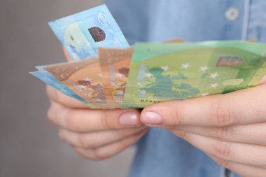 Açık gri arka planda euro banknotları sayan kadın, yakın plan