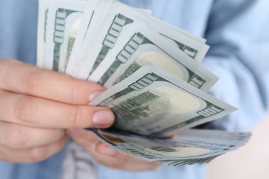 Açık gri arka planda dolar banknotları sayan kadın, yakın plan