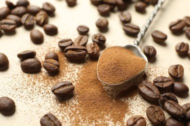 Bej arkaplanda hazır kahve ve fasulye, yakın plan.