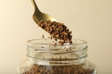 Bej arka planda kaşıkla hazır kahve içmek, yakın plan.