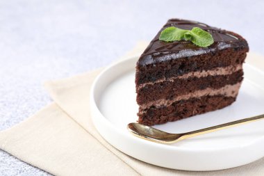 Gri masadaki naneli ve kaşıklı lezzetli çikolatalı pasta.