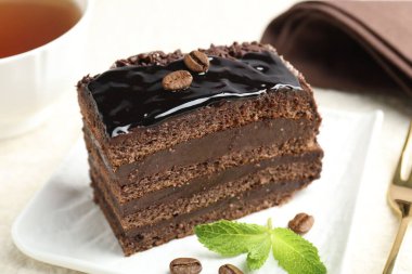 Bir parça çikolatalı kek, beyaz masada nane şekeri ile servis ediliyor, yakın plan.