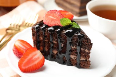 Çilek ve çayla servis edilen bir parça çikolatalı kek, yakın plan.