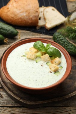 Salatalık çorbası, kızarmış ekmek, fesleğen, ekmek ve sebzeler ahşap masada, yakın plan.