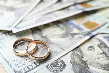 Altın alyanslar ve dolar banknotları, yakın plan. Metin için boşluk