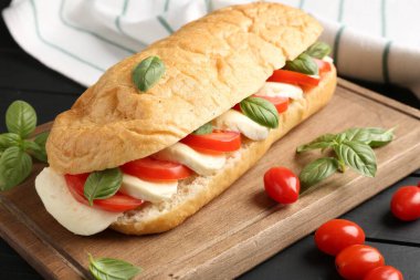 Mozarella peynirli, domatesli, fesleğenli, siyah ahşap masa, yakın plan.