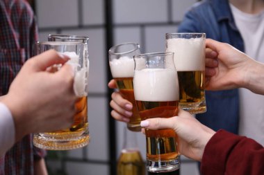 Arkadaşlar bira bardaklarını tokuşturur, yakın plan