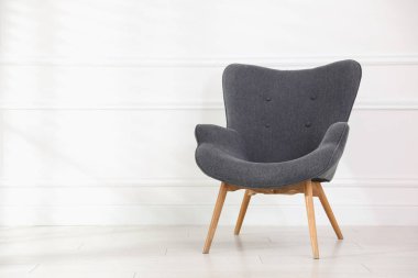 Beyaz duvarın yanındaki rahat gri koltuk, metin için boşluk.