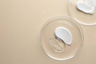 Petri kaplarında bej arka planda farklı kozmetik ürünleri var. Metin için boşluk